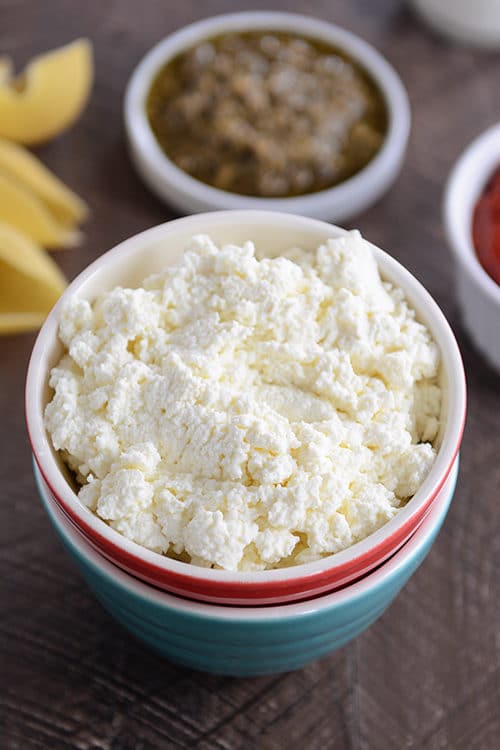 Top view of a red bowl full of homemade ricotta cheese. 