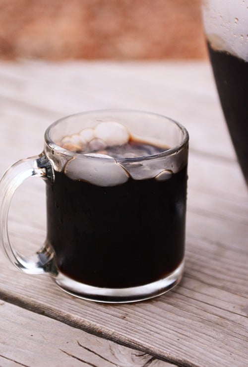 A clear glass cup of homemade root beer.