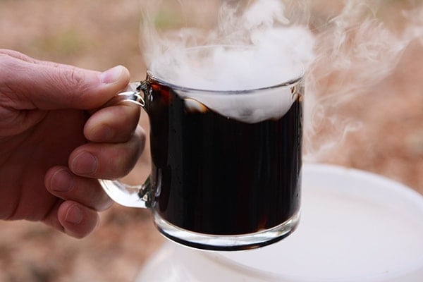 A mug of homemade root beer with dry ice steam coming out of the top.