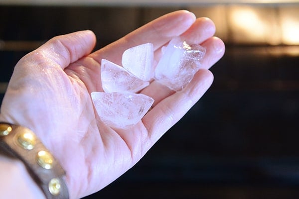 A hand holding 4 pieces of ice. 