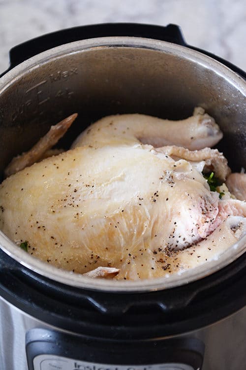 A cooked and seasoned whole chicken inside of an Instant Pot. 