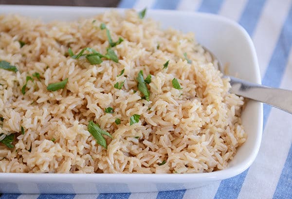 A white dish full of cooked brown rice and orzo pilaf. 