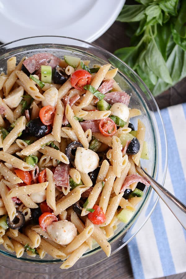 Top view of a pasta salad with olives, tomatoes, mozzarella, and onions.