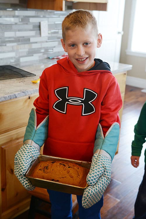 A little boy holding a cooked loaf of bread. 