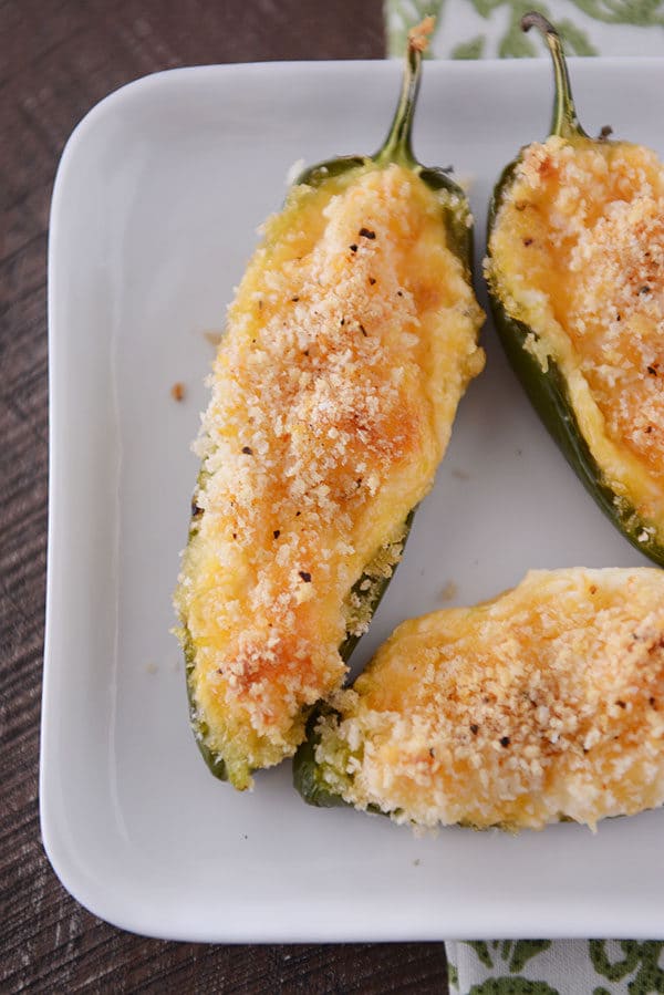 Top view of cheesy cooked jalapeno poppers on a white plate.