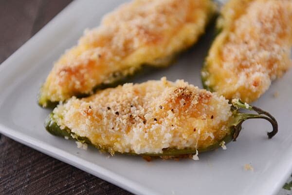 Cooked cheesy jalapeno poppers on a white platter.