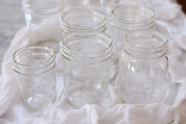 Five empty glass mason jars on a white towel.