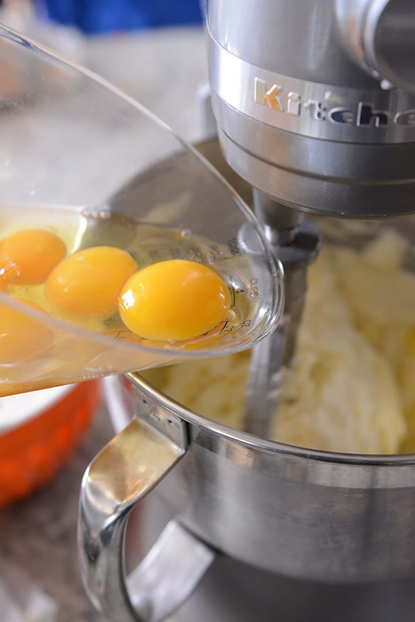 Raw eggs getting poured into a KitchenAid bowl.