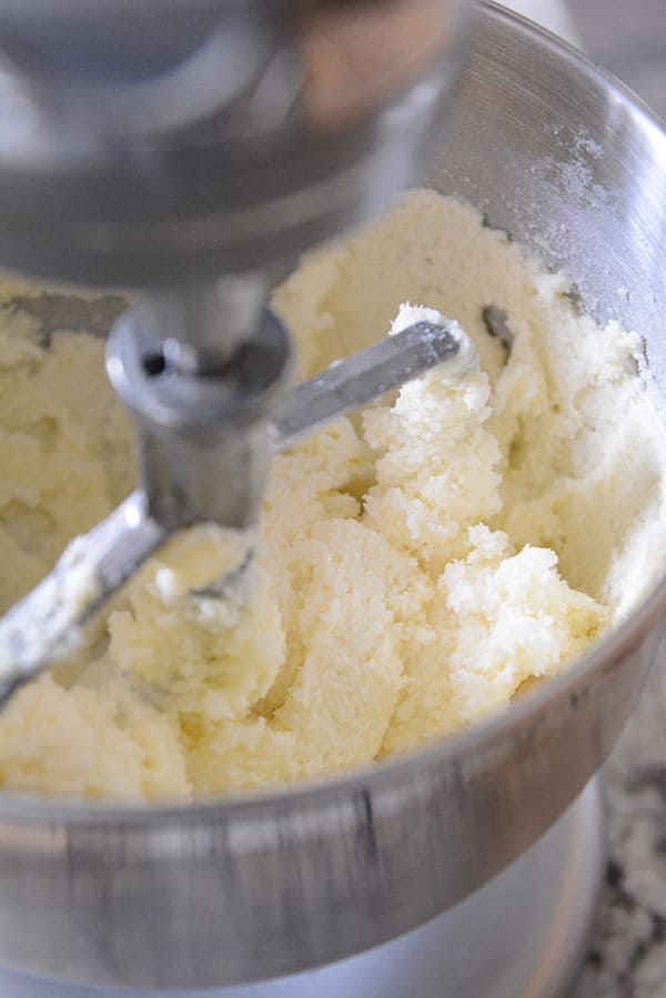 Butter and sugar inside a KitchenAid mixing bowl.