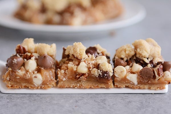 Three caramel pecan chocolate chip bars lined up in a row.