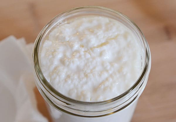 Top view of a mason jar full of kefir grains and milk.