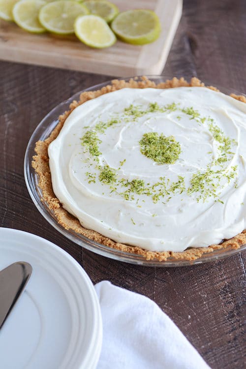 A key lime cheesecake topped with white chocolate and sprinkled with lime zest. 