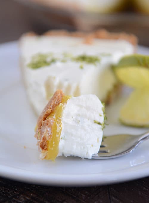 A slice of key lime cheesecake with a fork taking a bite out.