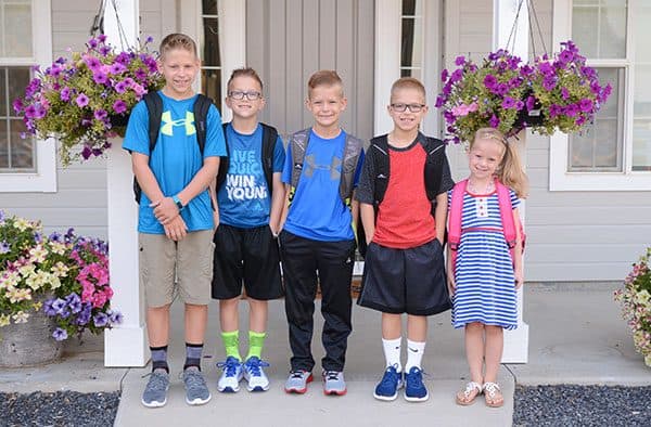 Five kids standing on their front porch on their first day of school.