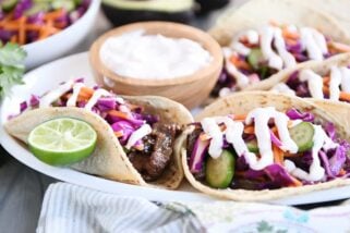 Korean beef tacos with slaw and sauce on white platter.