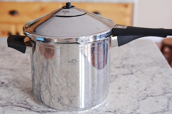 A stovetop pressure cooker sitting on a granite countertop.