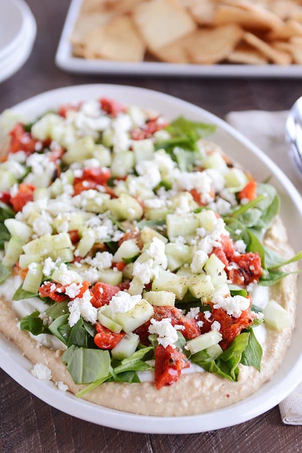 A white oval bowl of Greek hummus dip. 