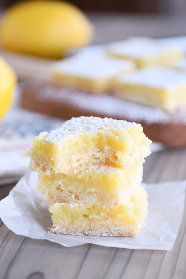 The best lemon bars stacked on each other and bite taken out of top lemon bar.