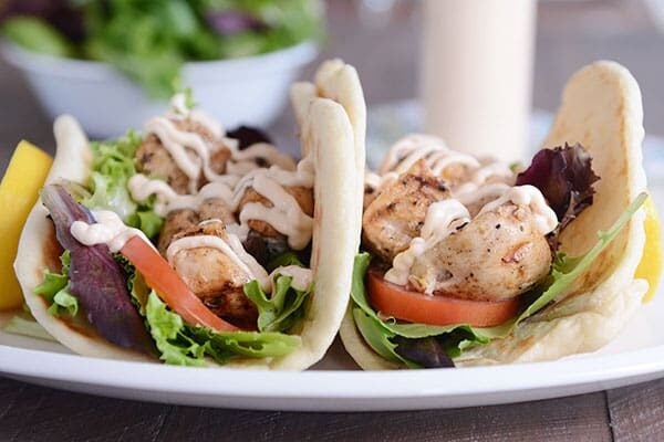 Two chicken lettuce wraps filled with veggies and drizzled with sauce.