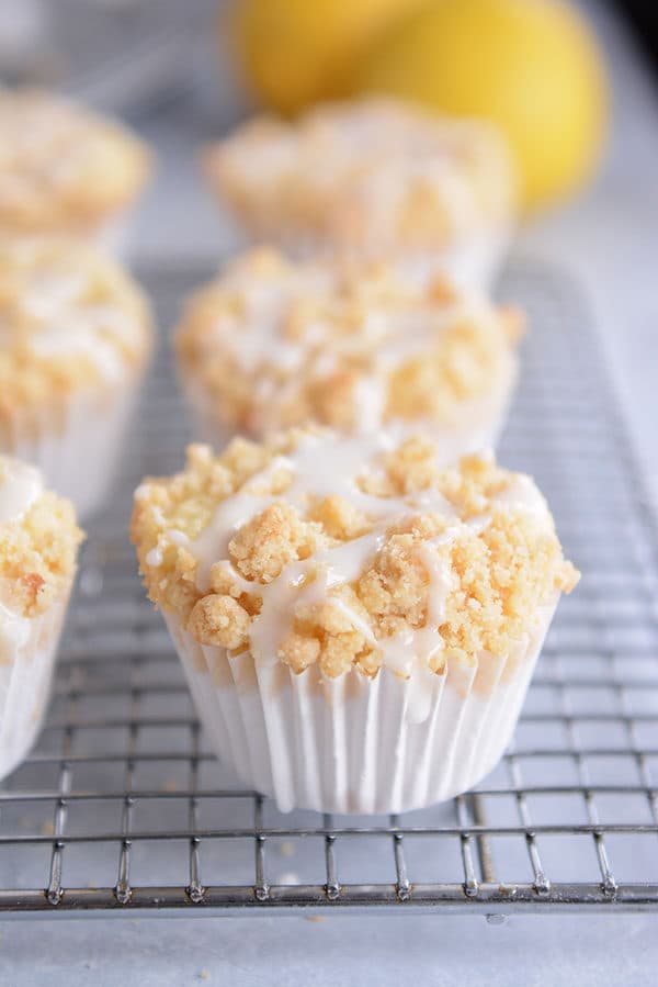 Streusel-topped lemon muffins with a drizzle of frosting on each one.