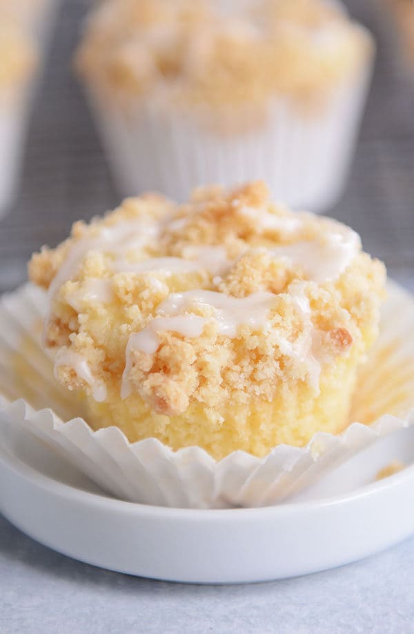 An unwrapped lemon crumb muffin with a drizzle of frosting on top.