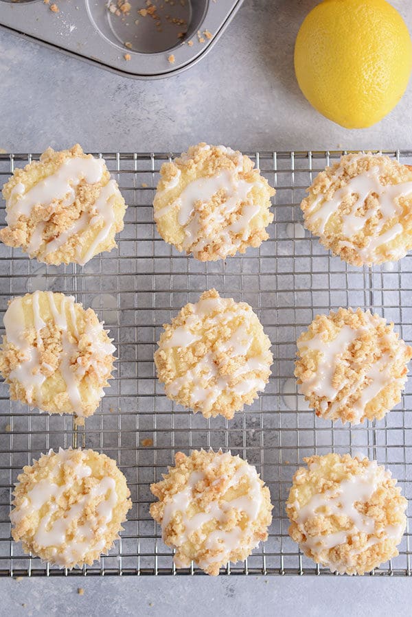 Top view of nine frosting drizzled lemon crumb muffins on a cooling rack.