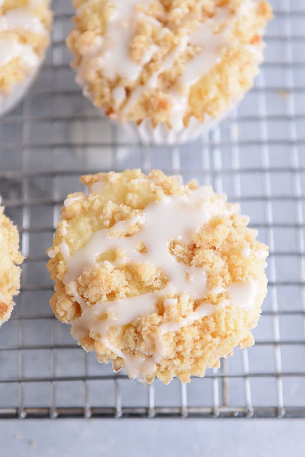 Top view of frosting drizzled lemon crumb muffins on a cooling rack.