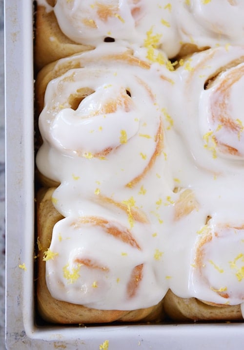 Lemon sticky buns with glaze and lemon zest in metal pan.