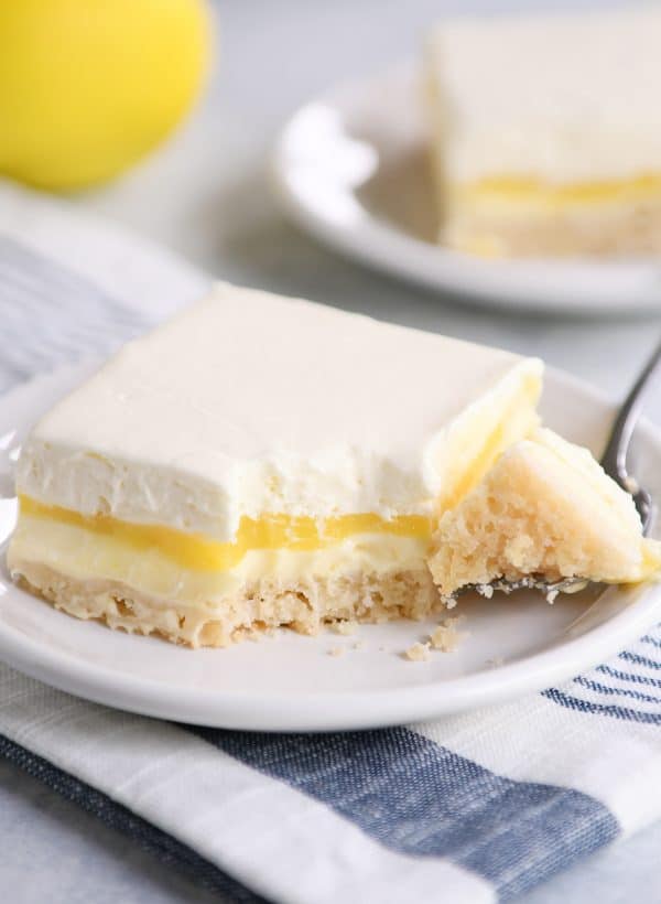 Lemon truffle shortbread bar on white plate with a bite taken out.
