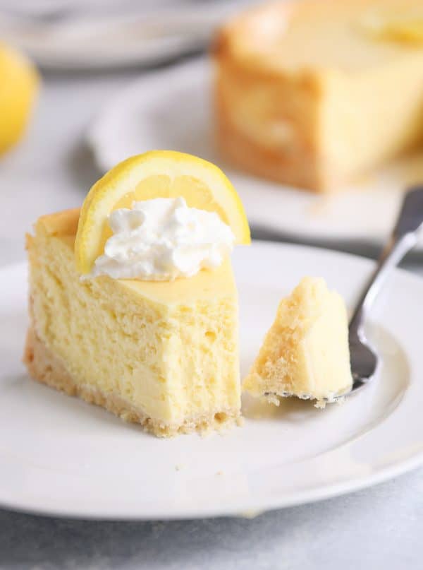 Slice of lemon white chocolate cheesecake on white plate.