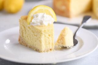 Slice of lemon white chocolate cheesecake on white plate.