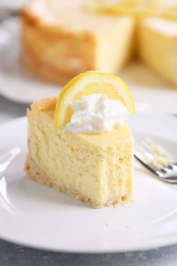 Slice of lemon white chocolate cheesecake on white plate.