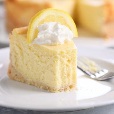 Slice of lemon white chocolate cheesecake on white plate.