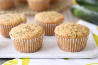 Several lemon poppy seed zucchini muffins on white plate.