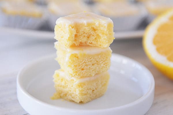 Three lemon brownies stacked on top of each other with a bite taken out of the top one.