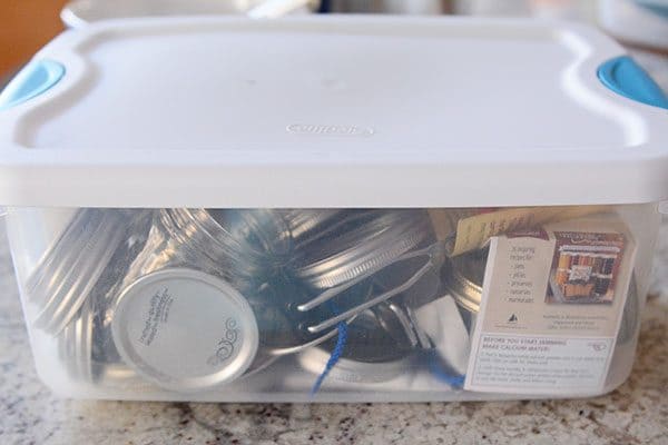 A tupperware full of canning lids and canning supplies.