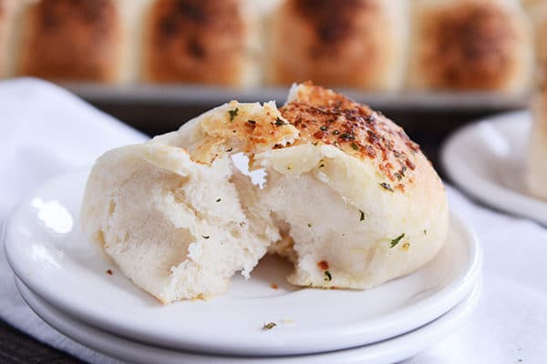 Asiago herb dinner roll on a white plate.