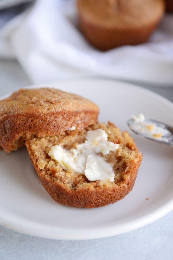 A bran muffin split in half with butter spread on it. 