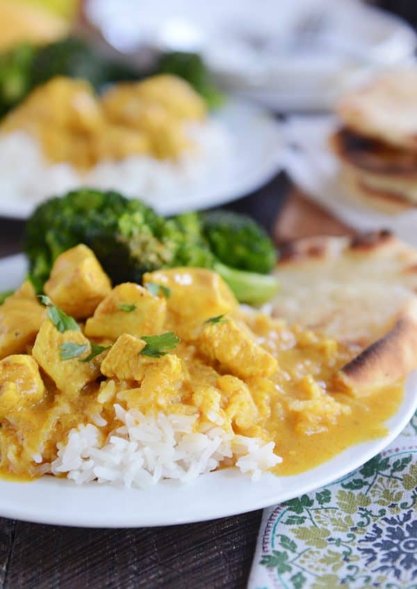 Thai chicken mango red curry sauce over white rice on white plate.