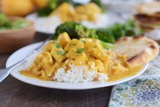 Thai chicken mango red curry sauce over white rice on white plate.