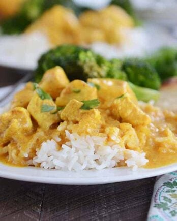 Thai chicken mango red curry sauce over white rice on white plate.