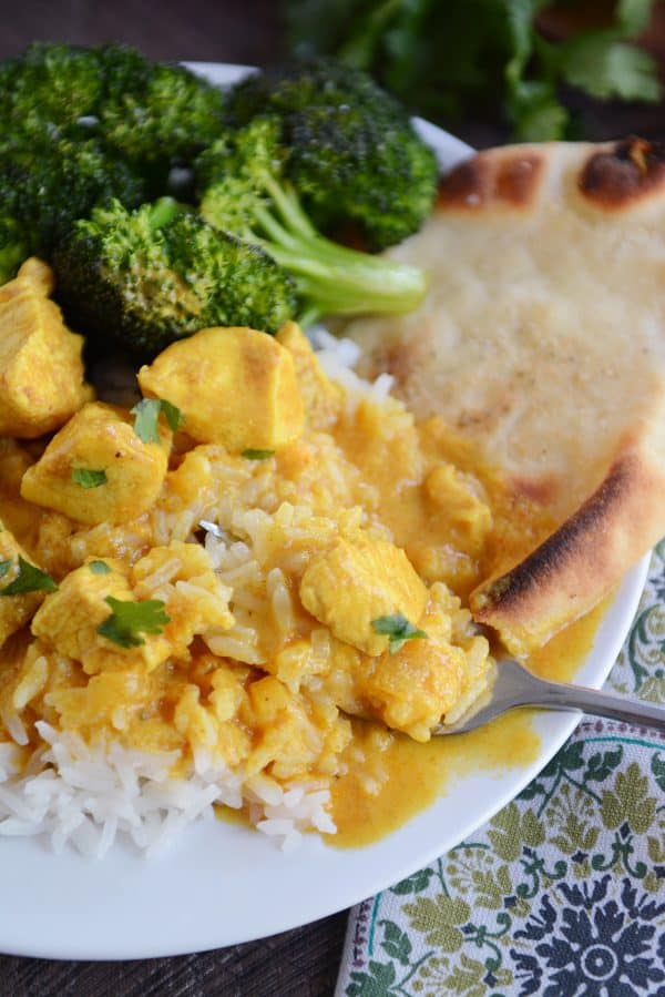 Thai chicken mango red curry sauce over white rice on white plate.