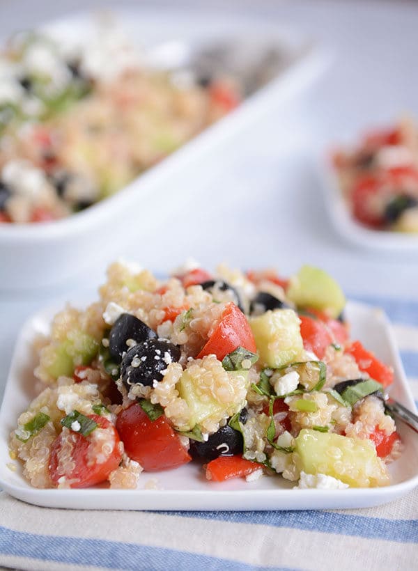 A square white plate of Mediterranean quinoa and vegetable salad. 