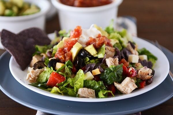 A white plate filled with Mexican chopped salad and cubes of chocolate and cheese.