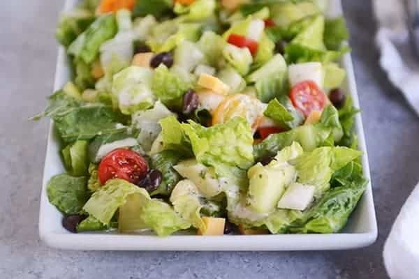 Chopped romaine salad with black beans, cubes of cheese, and cherry tomatoes sprinkled throughout.