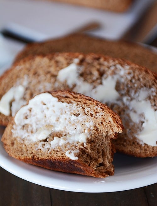 Slices of bread with butter slathered on the top. The front piece of bread has a bite taken out.