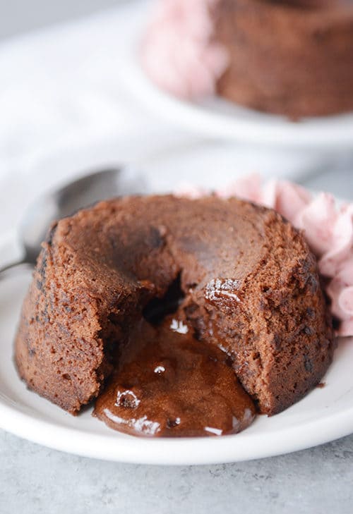 A chocolate molten lava cake with a bite taken out and fudge coming out the middle.