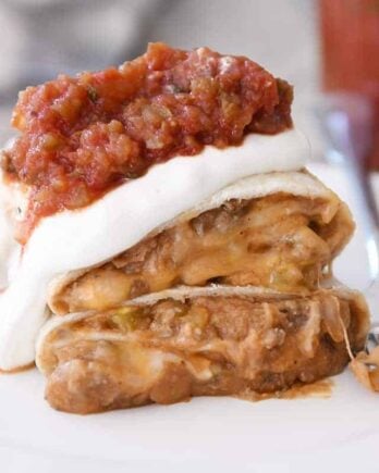 Freezer beef and bean burrito cut in half covered in salsa and sour cream.