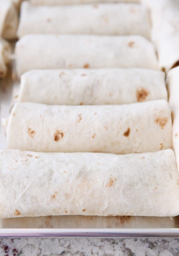 Rolled freezer burritos on sheet pan.