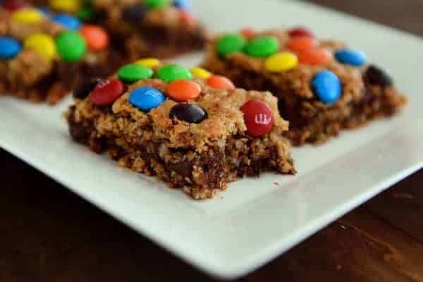 Cut up M&M topped chocolate oat bars on a white platter.